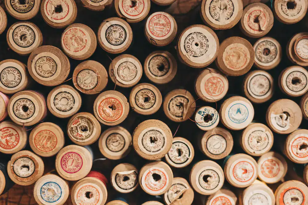 Close up of a wooden counter with sewing patterns and threads