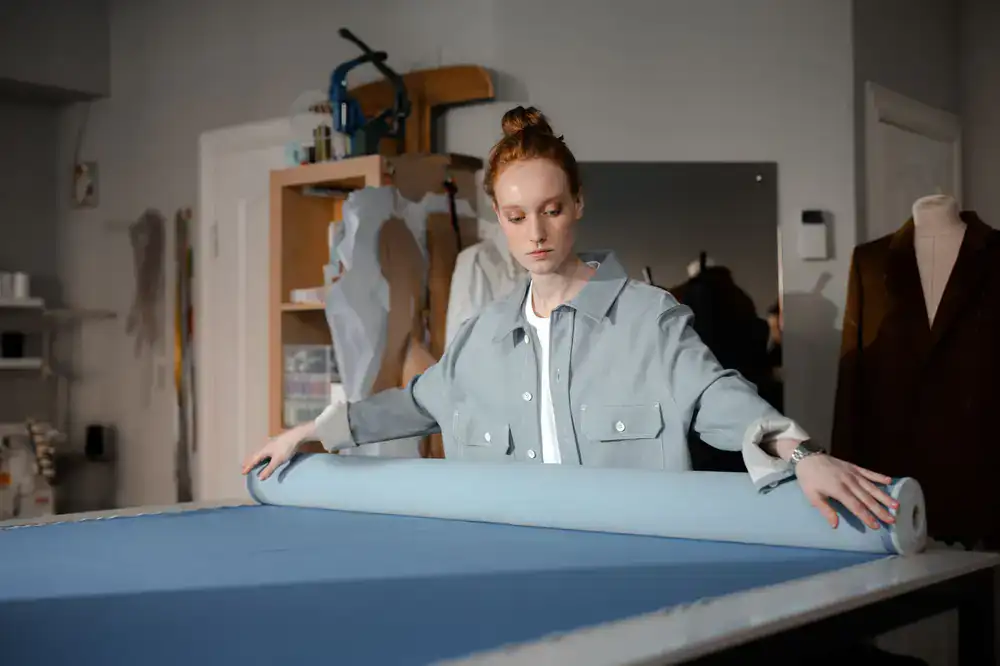 Shopkeeper measuring and cutting fabric carefully from a large roll
